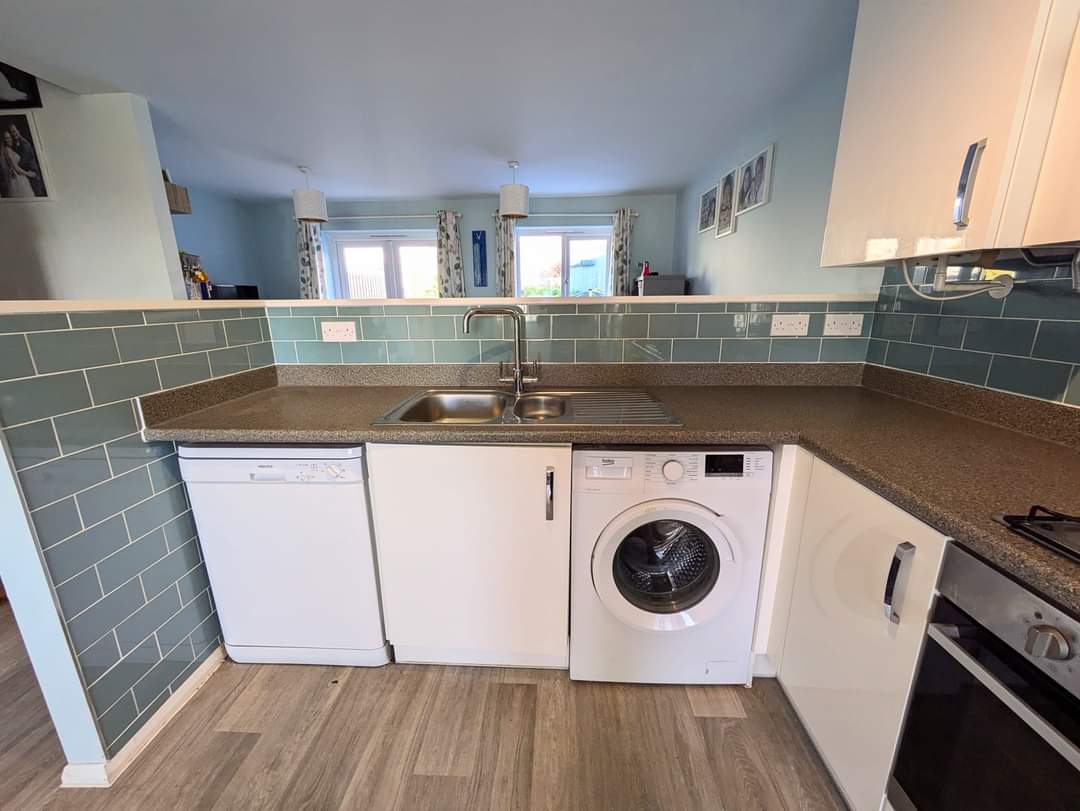 Fitted kitchen with a sage green tiled splashback and new worktop